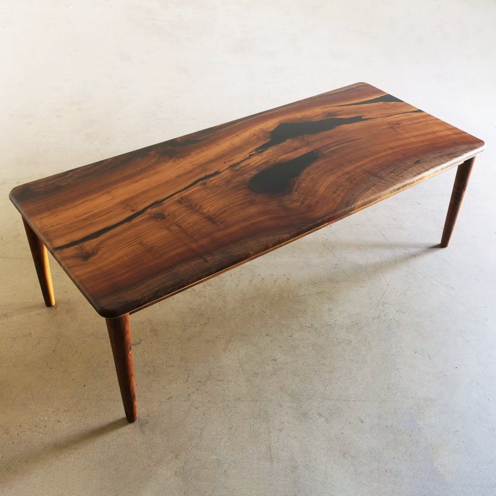 Slab table with black epoxy resin filling in voids made in mid century modern style.