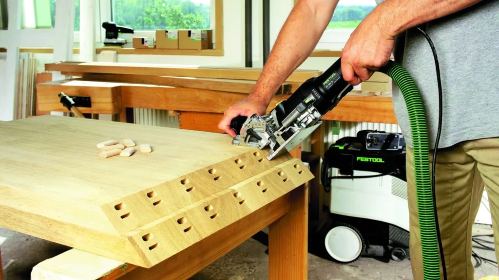 Festool Domino joiner creating mortises along the edge of a wooden panel for floating tenon joinery