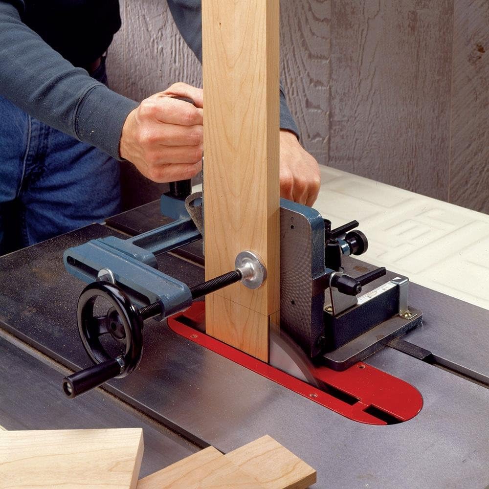 Cast iron tenoning jig clamped to a wooden workpiece being used on a table saw to cut a tenon shoulder